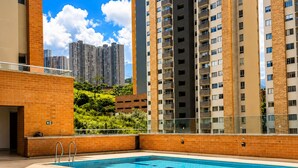 Ein Pool mit Blick auf hohe Gebäude und Grünflächen.