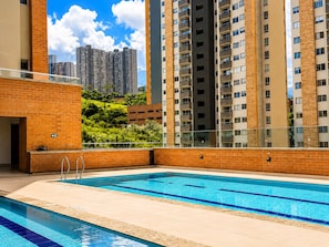 Ein Pool mit Blick auf hohe Gebäude und Grünflächen.