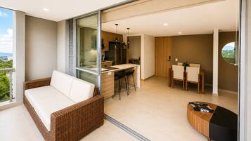 A modern living room with a sofa, a dining area, and a kitchen.