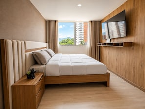 Ein modernes Schlafzimmer mit einem Holzkopfteil, einem Bett mit weißer Bettwäsche, einem Nachttisch, einem an der Wand montierten Fernseher und einem Fenster mit Blick auf Gebäude und Grünflächen.