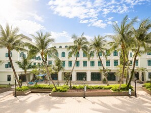 A hotel with a symmetrical facade, multiple windows, and palm trees in the foreground. - Cosi Beach Hotel Phu Quoc - Sunset (Phu Quoc)