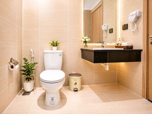 A modern bathroom with a toilet, sink, and a mirror with a hairdryer. - Cosi Beach Hotel Phu Quoc - Sunset (Phu Quoc)