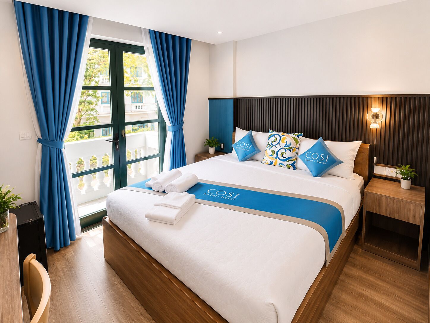 A hotel room with a bed, a nightstand, a potted plant, and a view through the window.