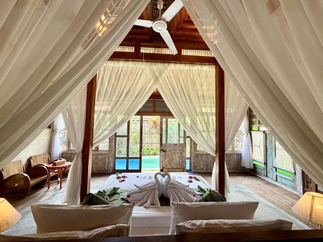 Una habitación con cama, ventilador de techo y vista al exterior.