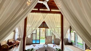 A room with a bed, a ceiling fan, and a view of the outdoors. - Sarini Joglo Villa by Manara (Sukawati)