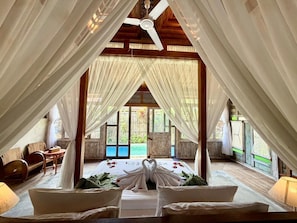 Una habitación con cama, ventilador de techo y vista al exterior.