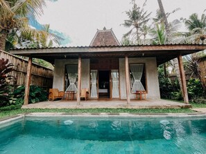 A poolside villa with a covered patio, a pool, and lush tropical vegetation.