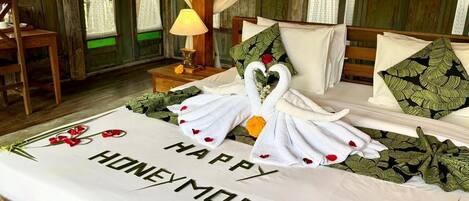 Una cama con un mensaje que dice 'Luna de miel feliz', un ramo de rosas rojas y una decoración con forma de cisne.