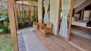 Een overdekt terras met houten meubels en een bed met hemelbed.