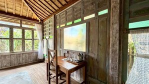 A rustic wooden room with a table and chairs, large windows, and a wooden ceiling. - Sarini Joglo Villa by Manara (Sukawati)