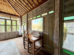 Una habitación rústica de madera con una mesa, sillas, ventanas amplias y techo de madera.