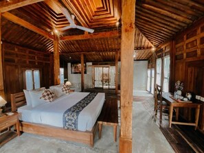 A wooden cabin-style bedroom with a large bed, wooden beams, and a dining area with a table and chairs. - Sarini Villas by Manara (Gianyar)