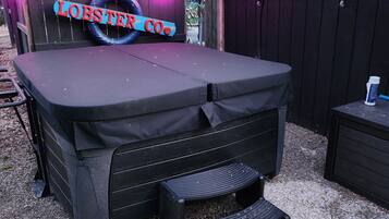 Un espace extérieur abrité avec une table et des bancs, une enseigne indiquant « LOBSTER CO », et une clôture en bois en arrière-plan.