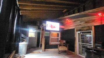 A room with a checkered carpet, a wooden ceiling, and a television screen.