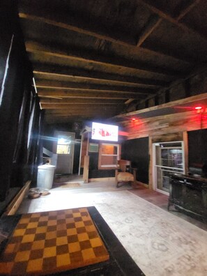 Une pièce avec un tapis à carreaux, un plafond en bois et un écran de télévision.