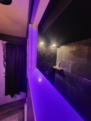 A modern bathroom with a stone wall, a sink, and a shower area.