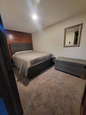 Une chambre à coucher avec un lit, une commode, un miroir et une tête de lit en bois.