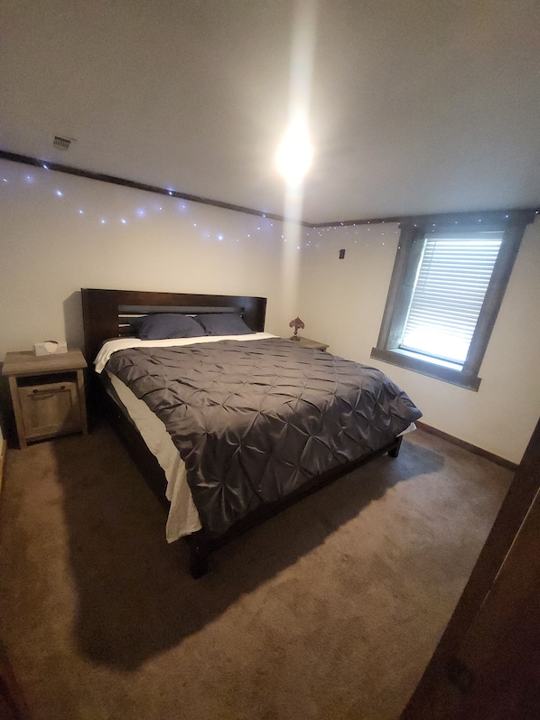 Une chambre à coucher avec un lit, une table de chevet et une fenêtre avec des stores.