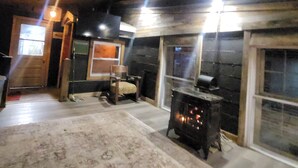A rustic interior with a fireplace, wooden beams, and a large window.