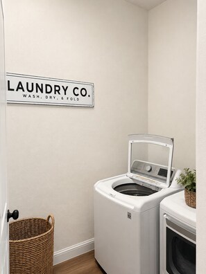 A laundry room with a sign reading 'LAUNDRY CO. WASH, DRY, & FOLD.' - Spacious 5-bedroom house in peaceful Arlington with AC (Arlington)