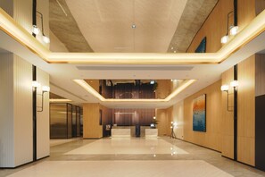 En rummelig lobby med en receptionsdisk, højt til loftet og et moderne design.