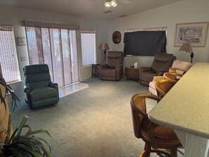 Ein Wohnzimmer mit einer Couch, zwei Sesseln, einem Couchtisch und einem Fernseher.
