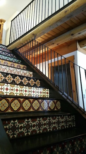 A staircase with ornate tile patterns and a wooden railing.