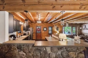 A rustic kitchen with wooden beams, a stone countertop, and modern appliances.