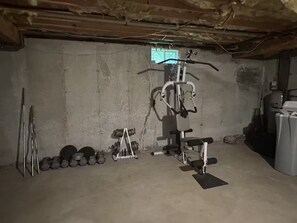 Ein Fitnessstudio mit einer Hantelbank, Kurzhanteln und einem Kabelzuggerät.