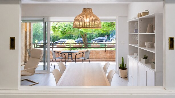 Ein modernes Interieur mit Essbereich, einer Pendelleuchte und Blick ins Freie.