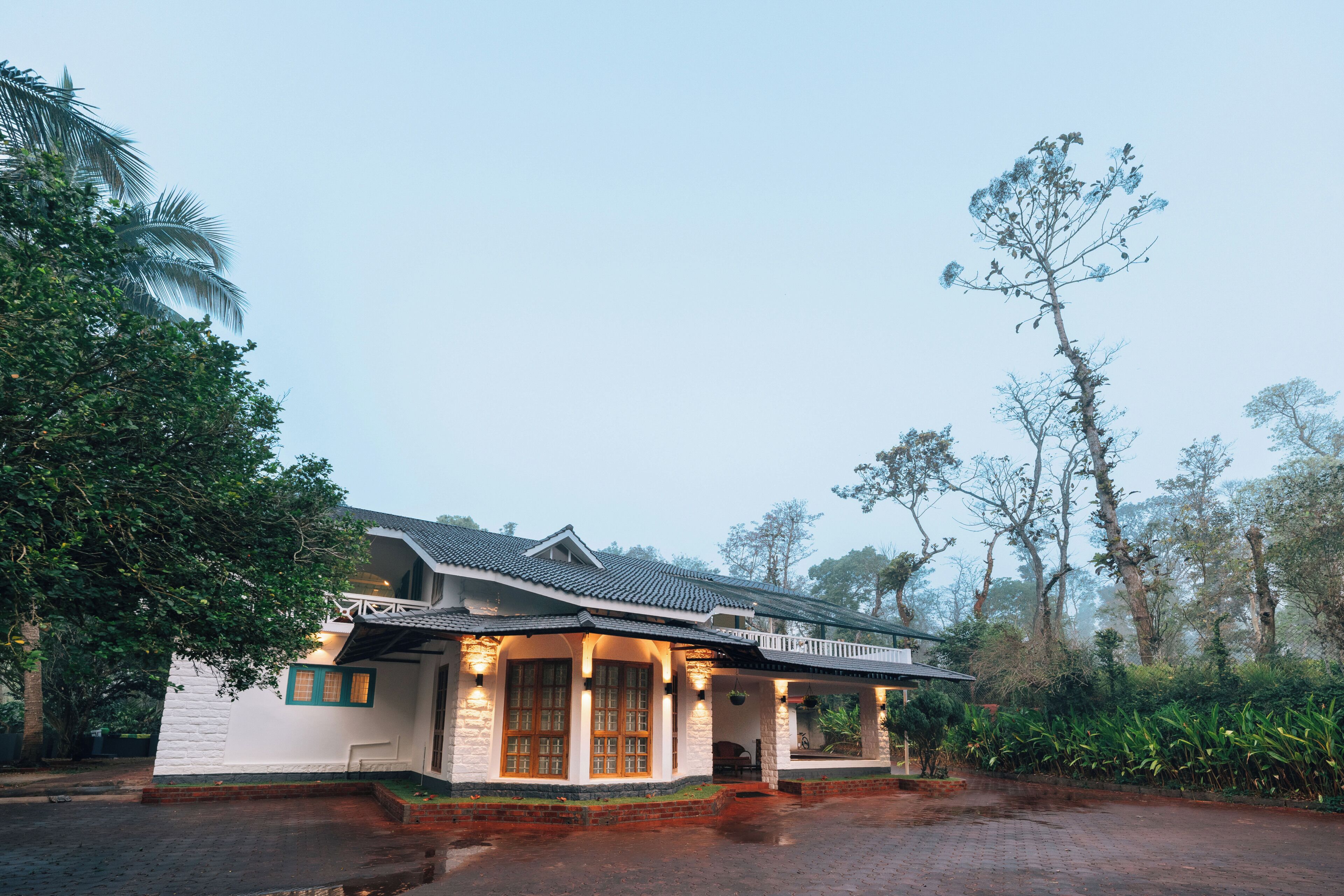 A traditional house with a porch, large windows, and a brick foundation.