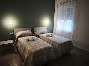 A hotel room with two beds, each with a headboard, a nightstand, and a wall-mounted light.