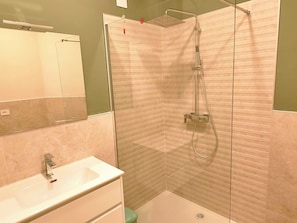 A bathroom with a glass-enclosed shower, a white sink, and a mirror.