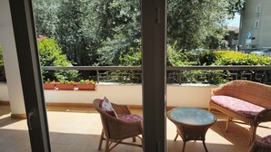 Un balcón con muebles de mimbre, una mesa de vidrio y plantas en macetas.