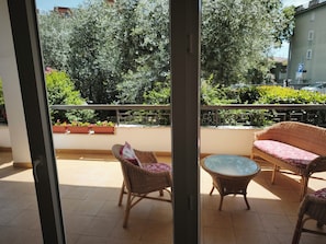 A balcony with wicker furniture, a glass table, and potted plants.