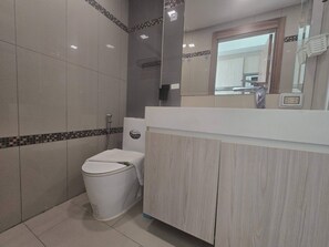 Een badkamer met toilet, douche en een wastafel met spiegel.