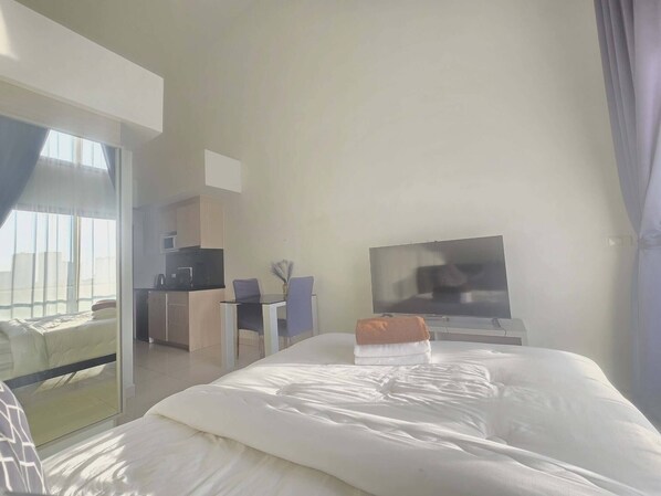 Een hotelkamer met een bed, een televisie, een bureau en een kitchenette.