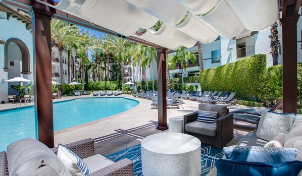 A poolside area with lounge chairs, a pool, and a covered seating area. - Furnished luxury apt, pool, sauna, great location (Los Angeles)