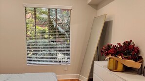 Un dormitorio con cama, cómoda, espejo y ventana con persianas.