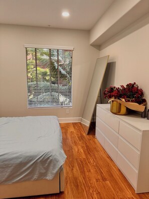 A bedroom with a bed, a dresser, a mirror, and a window with blinds. - Furnished luxury apt, pool, sauna, great location (Los Angeles)