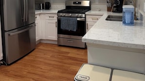 Una cocina moderna con armarios blancos, electrodomésticos de acero inoxidable y encimera de mármol.
