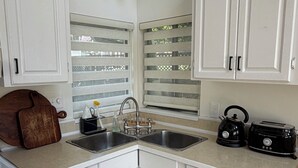 A kitchen with white cabinets, a double sink, a kettle, and a toaster.