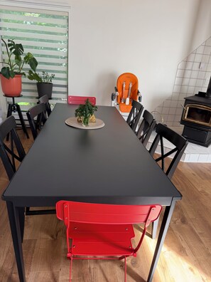 Ett matbord med stolar, en krukväxt och en röd stol.