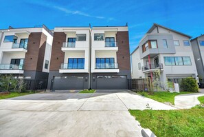 Un moderno edificio residencial de varios pisos con balcones, ventanas grandes y un césped bien cuidado.
