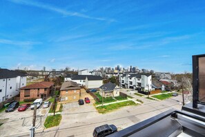 Un quartier résidentiel avec des maisons, un parking et, au loin, la silhouette de la ville.