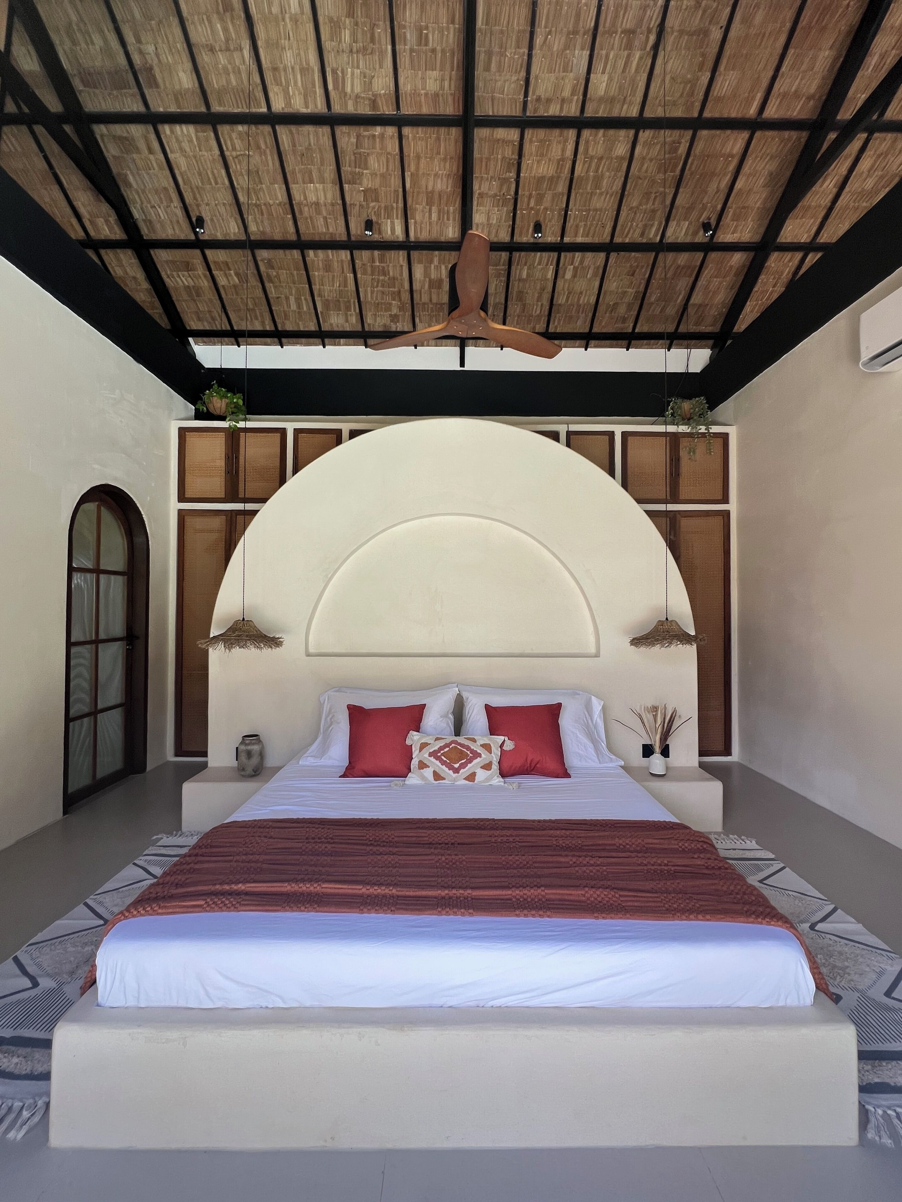 A bedroom with a large bed, a wooden ceiling, and a built-in wardrobe.