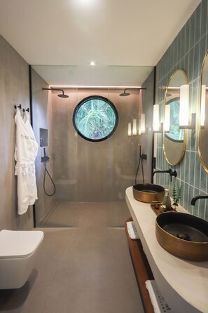 A modern bathroom with a round mirror, two sinks, a shower, and a towel rack. - Alma Villas (San Juan)