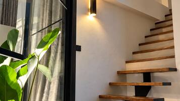 A modern staircase with wooden steps and black supports, illuminated by wall-mounted lights.
