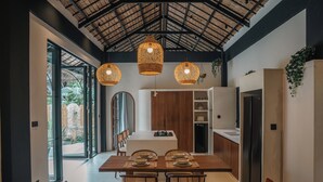 A modern kitchen with a dining area, large windows, and hanging wicker lights. - Alma Villas (San Juan)