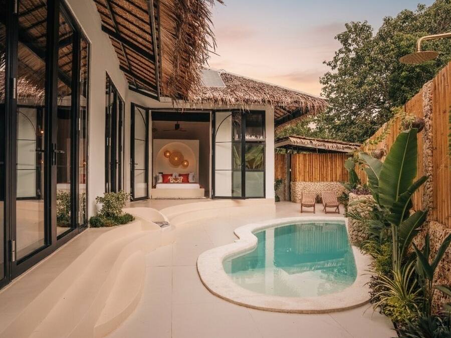 Una casa moderna con piscina, grandes puertas de cristal y techo de paja.